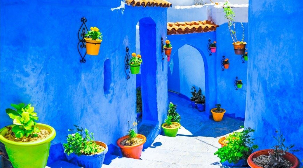 Stairs leading down between local houses painted in blue with colourful plant pots